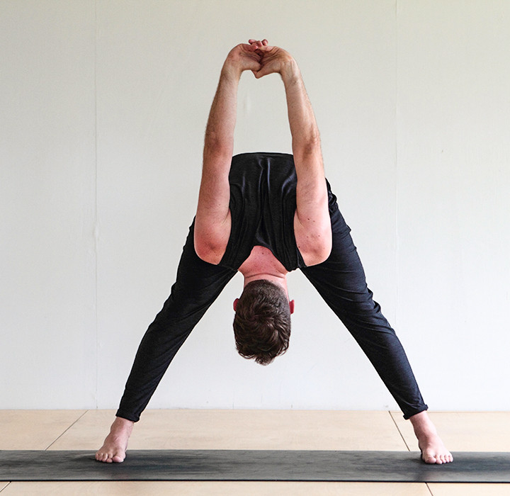 man doing Wide-legged Forward Bend yoga (Prasarita Padottanasana)