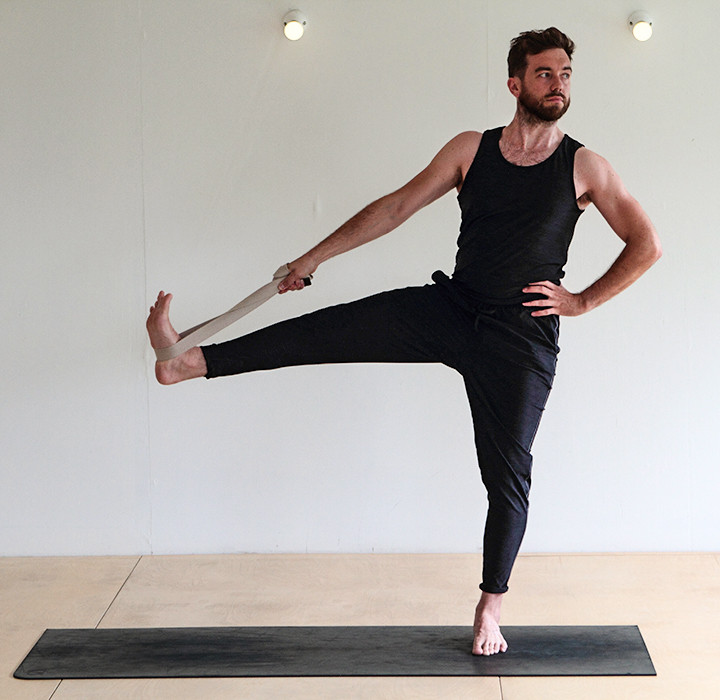 Man doing yoga supported Tree Pose with strap