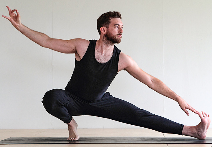 Man doing advanced yoga Side Ninja (Skandasana)